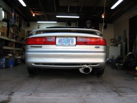 1996 Ford Probe - The rear of a silver coupe is parked in a garage, showing its taillights, license plate, and exhaust.