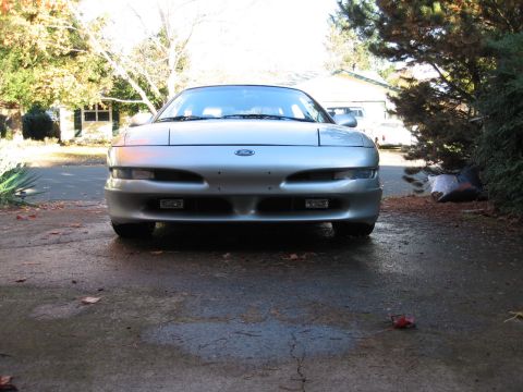 1996 Ford Probe - A silver Ford Probe is parked in a driveway on a wet day, with trees and a house in the background.