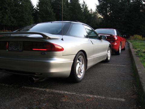 1996 Ford Probe - Two coupes, a silver 1996 Ford Probe and a red car, are parked next to each other.