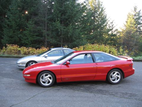 1996 Ford Probe - Two coupes parked side-by-side on asphalt with trees in the background.