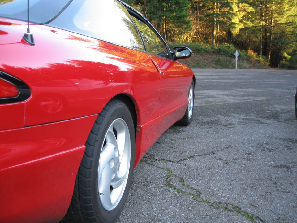 Side view of a red 1996 Ford Probe with a black roof and antenna