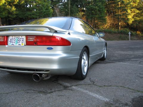 1996 Ford Probe - A silver Ford Probe is parked on asphalt with trees in the background.