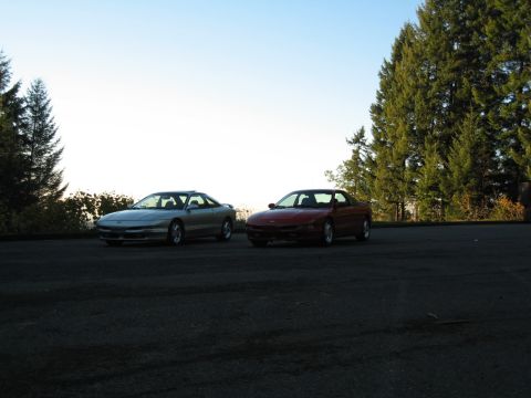 1996 Ford Probe - Two Ford Probe coupes are parked on an asphalt surface with a clear sky and trees in the background.