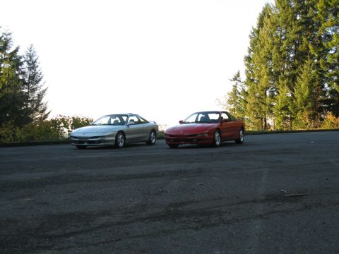 1996 Ford Probe - A silver and a red Ford Probe are parked side-by-side on a paved surface with trees in the background.