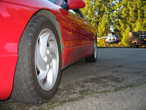 1996 Ford Probe - Side view of a red car, with a helicopter and truck parked behind it.