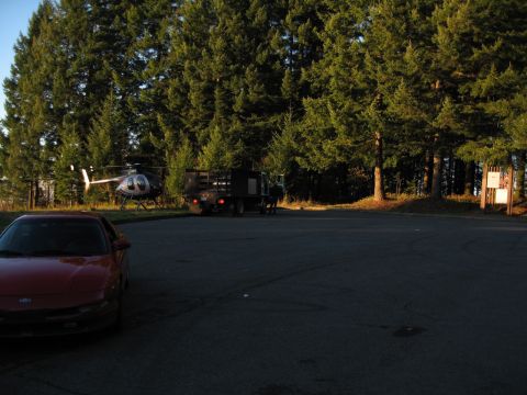 1996 Ford Probe - A red sports car is parked in a lot with a helicopter and truck nearby.