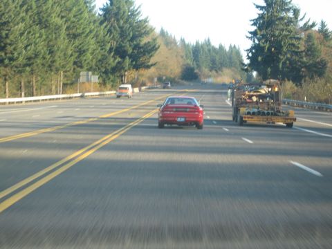 1996 Ford Probe - Multiple vehicles on a highway, including a red car and a truck hauling materials.