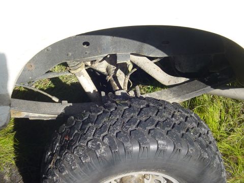 1989 Ford Bronco - Close-up of the rear suspension and tire of a white vehicle.
