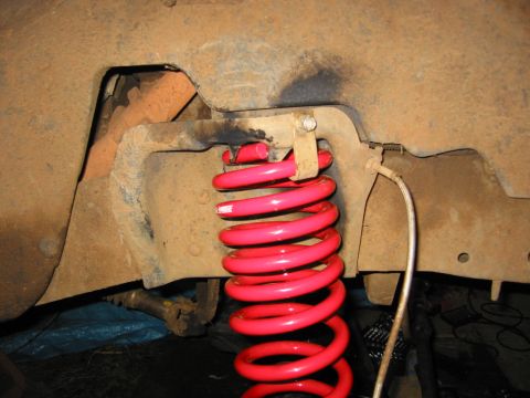 1991 Ford Explorer - Close-up of a bright red coil spring in a vehicle's suspension system.