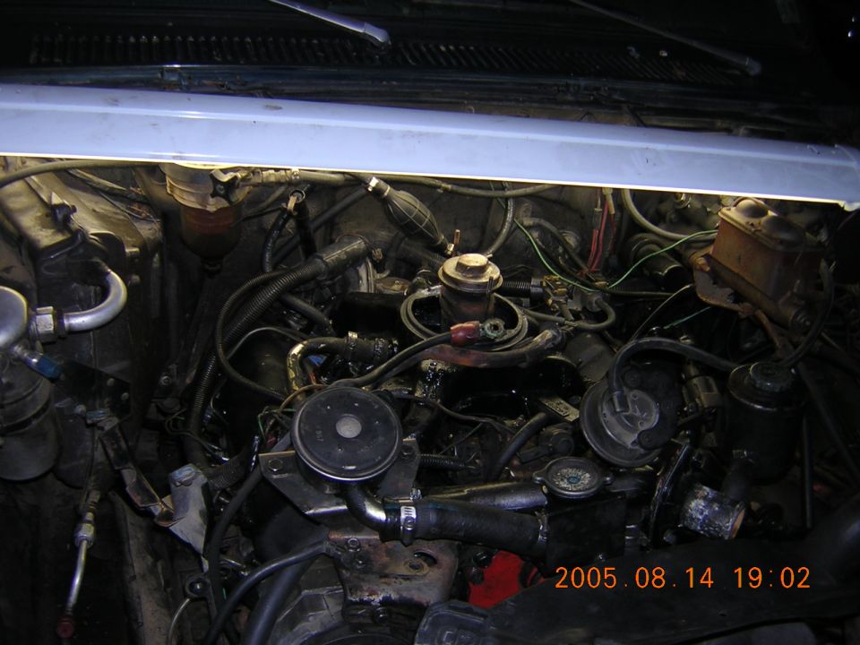 Grimy engine bay of an older pickup shot from above with hood open, 2005 date stamp