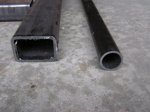 2000 Chevrolet Tahoe - Two pieces of metal tubing, one square and one round, lie on a concrete surface.