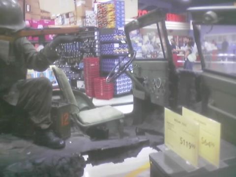1990 Ford Bronco - military-style open vehicle with a uniformed mannequin driver is displayed inside an auto parts store with price tags reading $119 and $64.