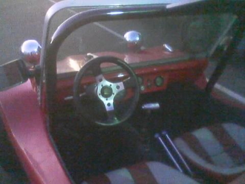 1990 Ford Bronco - cockpit of a dune buggy with a small chrome-spoke steering wheel, roll bar, shifter and red-and-white striped upholstery.