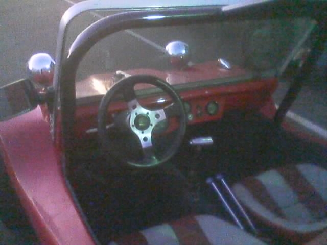 Interior of a dune buggy showing steering wheel, roll bar and striped seats