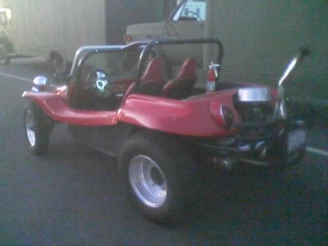 1990 Ford Bronco - red fiberglass dune buggy with a roll cage and chrome rear wheel parked near a vehicle in a dim garage setting.