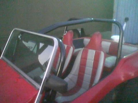 1990 Ford Bronco - Close interior view of a red dune buggy showing red-and-white vertically striped bucket seats and a folded-down windshield frame.