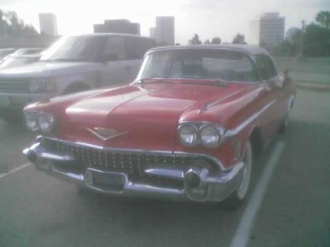 1968 Ford Mustang - A red 1958 Cadillac Eldorado convertible is parked in a lot, with a modern SUV behind it.