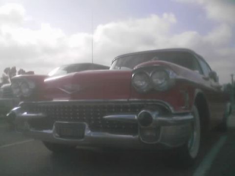 1968 Ford Mustang - A red 1958 Cadillac is parked, showing its distinctive front grille and headlights under a cloudy sky.