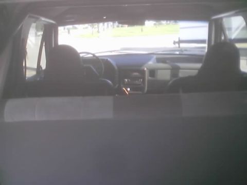 1990 Ford Bronco - Interior of a truck or SUV showing the dashboard and front seats, with a grassy area visible through the windshield.
