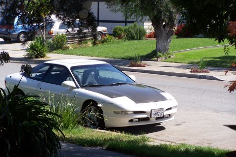 1997 Ford Probe - A white 1997 Ford Probe is parked curbside on a sunny day, with two other vehicles visible in the background.