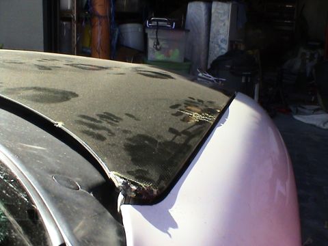 1997 Ford Probe - The damaged carbon fiber hood of a car is visible in this close-up shot.
