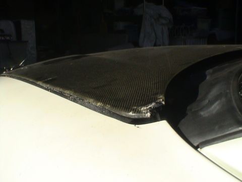 1997 Ford Probe - Close-up of damaged carbon fiber hood edge with visible fraying and impact.