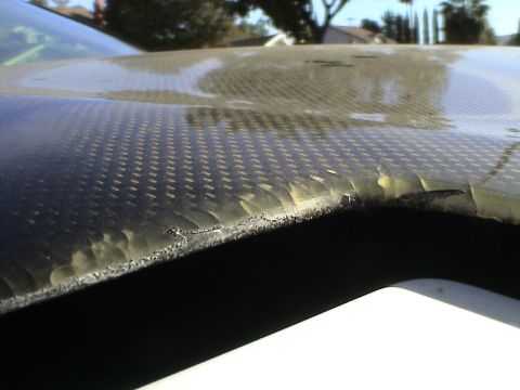 1997 Ford Probe - The edge of a carbon fiber hood shows delamination and damage.