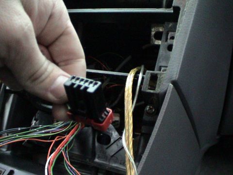 1997 Ford Probe - A hand disconnects the wiring harness for a car stereo system.