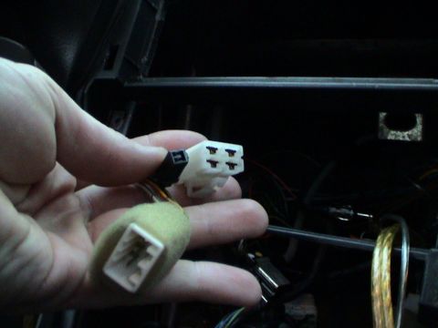 1997 Ford Probe - Close-up of a hand holding car stereo wiring harness connectors, likely for an aftermarket installation.