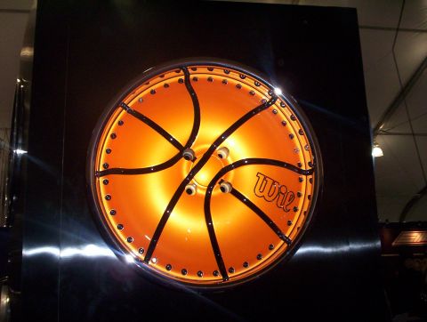 1998 Ford Crown Victoria - illuminated custom wheel styled like an orange-and-black basketball with the brand Wic, displayed on a black panel at a show.