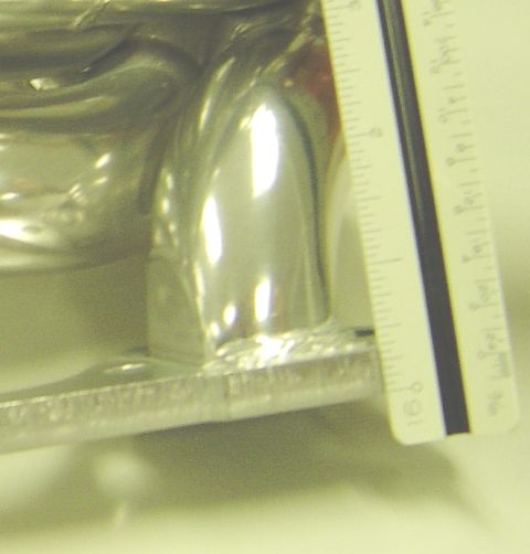 1986 Ford Bronco - A ruler is placed next to a polished metal exhaust manifold, indicating its dimensions.