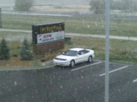 1996 Ford Probe - A white coupe is parked in a lot during a snowfall, with a business sign in the background.