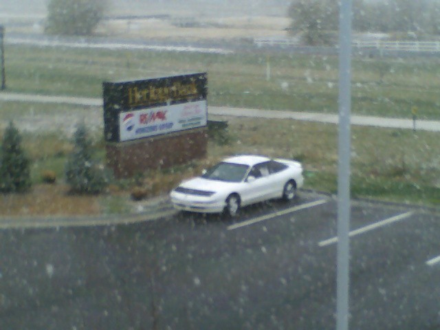 White coupe parked outside a building with a sign that says Heritage Bank and RE/MAX