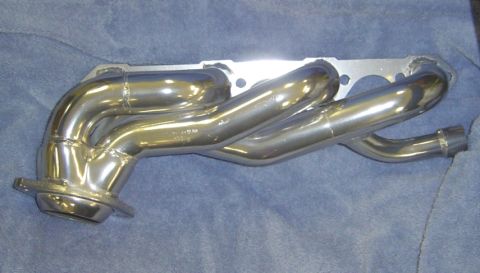 1986 Ford Bronco - A shiny chrome exhaust manifold is displayed on a blue fabric surface.
