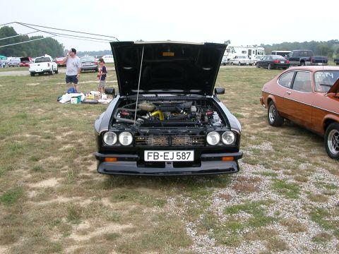 1981 Ford Mustang - Two Capris parked on grass, one with its hood open revealing the engine bay.
