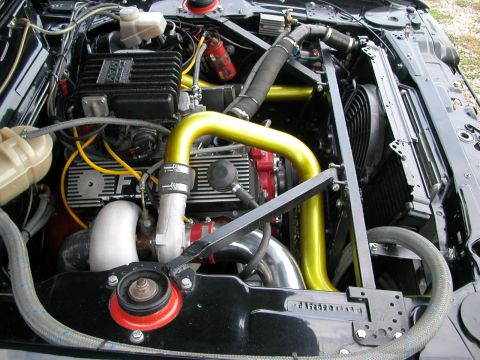 1981 Ford Mustang - A close-up view of a modified engine bay, highlighting custom yellow piping and turbo components.