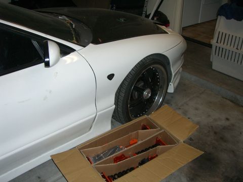 1996 Ford Probe - A white sports coupe is parked in a garage next to a box containing new suspension components.