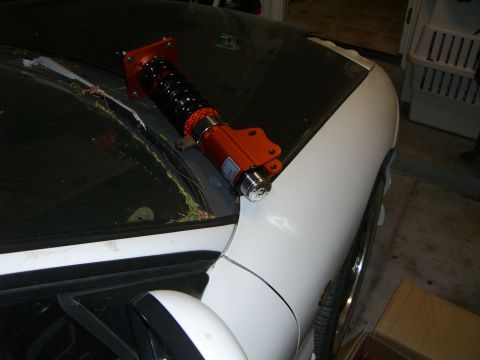 1996 Ford Probe - An orange coilover suspension part is placed on the hood of a white car, obscuring the windshield.