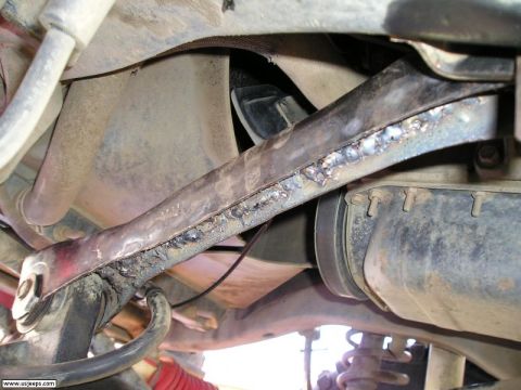 1989 Ford Bronco - This photo shows a heavily modified suspension component with visible welding marks underneath a vehicle.