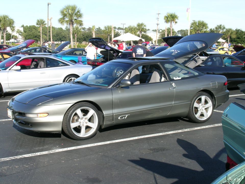 Gray Ford Probe GT with its hood and trunk open, parked in a lot with other cars
