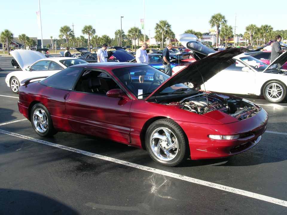 Red 1993 Ford Probe with hood open, parked at a car show