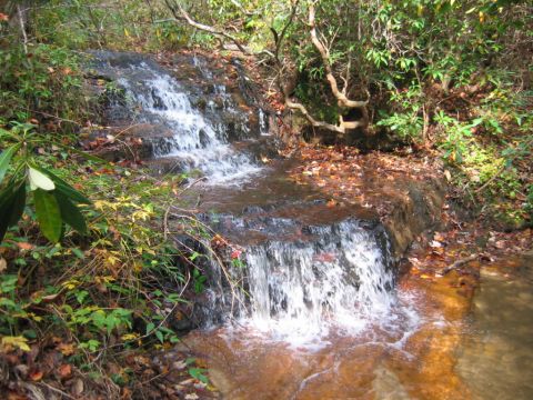 1985 Ford LTD Crown Victoria - A multi-tiered waterfall flows through a wooded area during autumn.