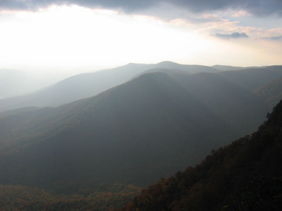Hazy mountain range with sun breaking through clouds
