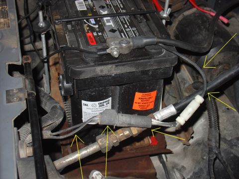 1988 Ford Bronco - Close-up view of a car battery and associated wiring, with yellow arrows highlighting specific components.