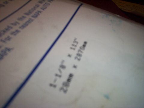1998 Ford Crown Victoria - Out-of-focus photo of a parts box label with belt dimensions, too blurry to classify as a document.