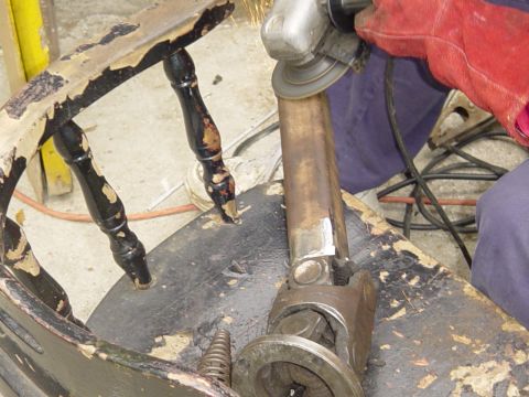 1989 Ford Bronco - Angle grinder in use on a metal part, with a broken chair in the foreground.