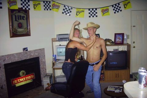 1989 Ford Bronco - A man and woman pose playfully in a room decorated with racing flags and beer memorabilia.