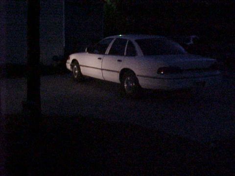1993 Ford Crown Victoria - A white 1993 Ford Crown Victoria sedan is parked outdoors at night.