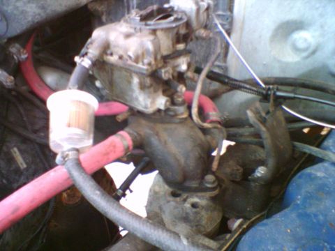 1985 Ford F-150 - Close-up view of an engine's carburetor and fuel filter assembly, with prominent red hoses.