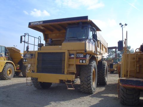 1966 International School Bus - A Caterpillar 773D dump truck is parked outdoors, with other heavy machinery visible in the background.